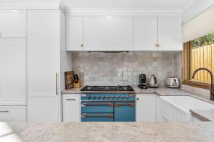 a kitchen with a blue stove and white cabinets at Fern House in Lorne +16 photos