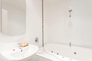 a white bathroom with a sink and a bath tub at Anglesea River Apartment 23 in Anglesea