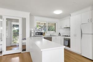 a white kitchen with white cabinets and a refrigerator at Beach Side in Aireys Inlet