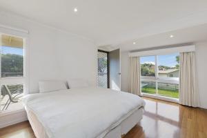 a white bedroom with a large bed and large windows at Beach Side in Aireys Inlet