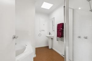 a white bathroom with a tub and a sink at Beach Side in Aireys Inlet