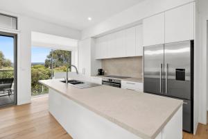 a kitchen with a stainless steel refrigerator and white cabinets at Aireys Sunset Beach House in Aireys Inlet