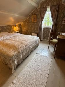 a bedroom with a bed and a chair and a window at Gammel stua AS in Andøya