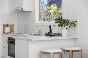 a white kitchen with two stools and a sink at AquaLuna Beach House in Aireys Inlet