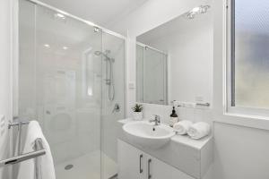a white bathroom with a sink and a shower at AquaLuna Beach House in Aireys Inlet