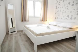 a white bed in a room with a mirror at Apartments Gabrijel in Vodice