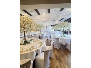 a banquet hall with white tables and chairs and trees at Hotel-Restaurant Krüger in Grafhorst