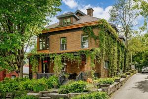 a brick house covered in ivy on a street at Charmant appartement dans maison patrimoniale in Sherbrooke