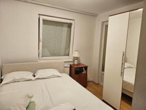 a white bedroom with a bed and a window at Apartman Dona in Bosanska Gradiška
