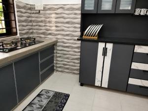 a kitchen with black and white cabinets and a rug at HomeStay with Serene Surrounding in Nibung Tebal +13 photos