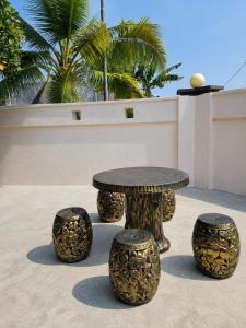 a table and stools with a table and palm trees at HomeStay with Serene Surrounding in Nibung Tebal