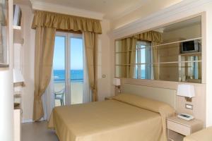 a bedroom with a bed with a view of the ocean at Hotel Caesar Paladium in Rimini
