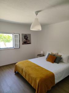 a bedroom with a large bed with a yellow blanket at Monte do Ti'Mota in São Lourenço de Mamporcão