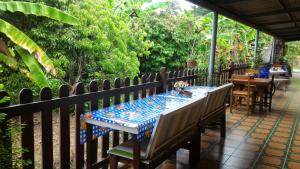 a table and chairs on a patio with a fence at Baan Benjathip in Amphawa