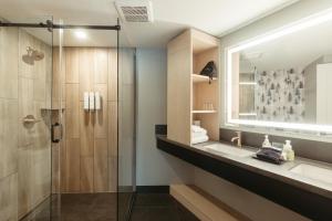 a bathroom with a shower and two sinks and a mirror at Everwild Canmore Hotel in Canmore +56 photos