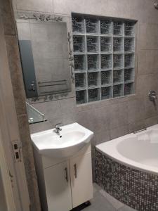 a bathroom with a sink and a tub and a mirror at Garden Route Retreat in George +37 photos