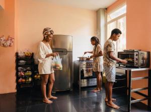 three people standing in a kitchen with a refrigerator at Odara Hostel & Guesthouse in Salvador