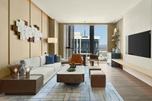 a living room with a couch and a tv at Beijing Marriott Hotel Huairou in Huairou