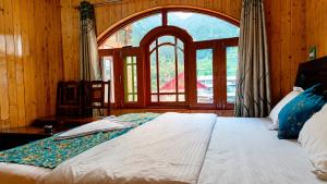 a bedroom with a large bed with a large window at Alpine Hub Gurez in Wāmpor