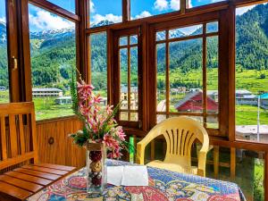a table with two chairs and a vase with flowers on it at Alpine Hub Gurez in Wāmpor