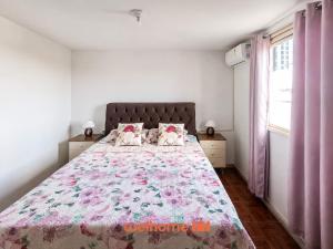 a bedroom with a large bed with a floral bedspread at Cobertura com Vista e Conforto no RS in Santo Ângelo
