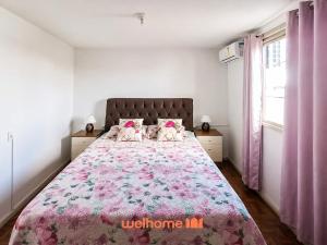 a bedroom with a large bed with a pink blanket at Cobertura com Vista e Conforto no RS in Santo Ângelo
