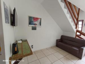 a living room with a couch and a television at Residencial Sol de Ibiraquera in Barra de Ibiraquera