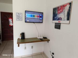 a room with a tv and a desk with a computer on a wall at Residencial Sol de Ibiraquera in Barra de Ibiraquera +31 photos