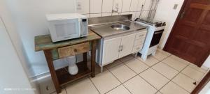 a small kitchen with a sink and a microwave at Residencial Sol de Ibiraquera in Barra de Ibiraquera