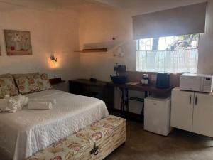 a bedroom with a bed and a desk with a microwave at Pousada Cantinho de Minas Da Tânia in Cabo Frio +80 photos