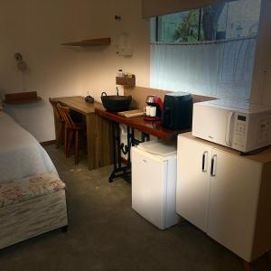 a room with a kitchen with a microwave and a counter at Pousada Cantinho de Minas Da Tânia in Cabo Frio