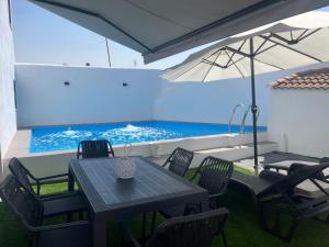 a table and chairs with an umbrella and a swimming pool at El Refugio de Navalcuervo 