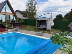 a swimming pool with an umbrella next to a house at A-Frame Wellness Villa with Private Pool, Sauna & Jacuzzi near Belgrade in Koraćica