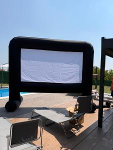 a large screen tv with two chairs and a table at A-Frame Wellness Villa with Private Pool, Sauna & Jacuzzi near Belgrade in Koraćica