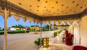 an outdoor pavilion with red chairs and a ceiling at Desert Luxury Camp & Resort Jaisalmer in Jaisalmer