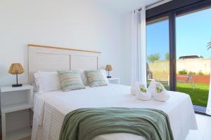 a bedroom with a white bed with a large window at Apartamentos turísticos El Pinar in Mogro