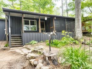 a black house with a tree stump in front of it at Cameron's Cottage at The Lake in Tallassee
