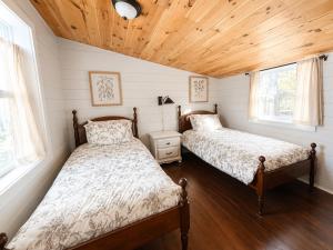 two beds in a small room with wooden ceilings at Cameron's Cottage at The Lake in Tallassee