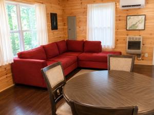 a living room with a red couch and a table at Cameron's Cottage at The Lake in Tallassee