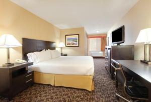 a hotel room with a large bed and a television at Holiday Inn Express Oakdale by IHG in Oakdale