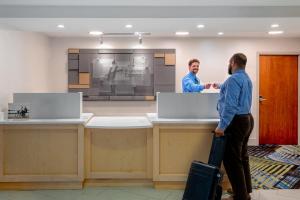 two men with luggage standing at a counter in an office at Holiday Inn Express Chapel Hill by IHG in Chapel Hill