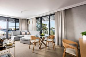 a living room with a couch and a table and chairs at Tradewinds Hotel and Suites Fremantle in Fremantle