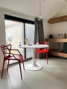 a white table and two red chairs in a room at Uitgerust voor Zaken in Heerenveen