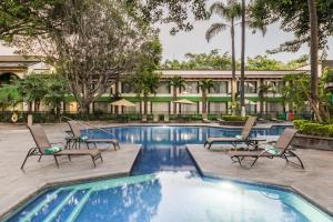 a pool at a hotel with chairs and a building at Holiday Inn Guadalajara Expo Plaza del Sol by IHG in Guadalajara