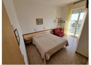 a bedroom with a bed and a red chair at Hotel Conti in Rimini +53 photos