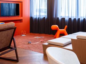 a living room with a table and an orange chair at Novotel Suites Colmar Centre in Colmar