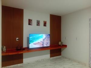 a tv on a shelf in a room at Casa ideal 6 quatros sendo 4 suítes 2 km do centro in Bananeiras