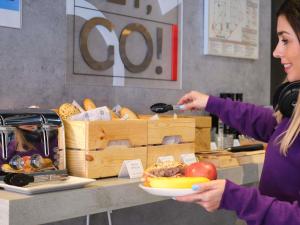 a woman is holding a plate of food at ibis budget Bilbao City in Bilbao