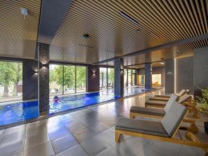 a large swimming pool in a building with a couch at Holiday studio with balcony, indoor pool, sauna in Polanica-Zdrój