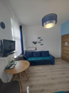 a living room with a blue couch and a table at Magnolia Home Rooms in Toruń